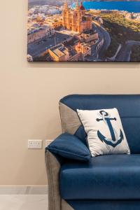 einen blauen Stuhl mit Kissen in einem Zimmer in der Unterkunft Aloha - Village Apartment 2 BR in Mellieha in Mellieħa
