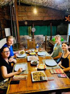 a group of people sitting around a table eating food at Pearl White House in Udawalawe