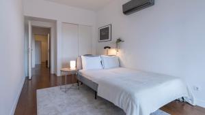 een witte slaapkamer met een groot bed en een tafel bij Classy 3BDR Property by LovelyStay in Lissabon