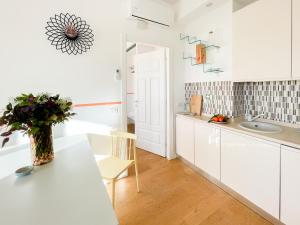 eine weiße Küche mit einem Tisch und einer Vase aus Blumen in der Unterkunft Alinari Boutique Apartments in Florenz