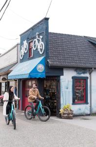 um homem e uma mulher a andar de bicicleta em frente a uma loja em Steveston Waterfront Hotel em Richmond