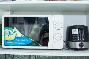 a microwave on a shelf next to a toaster at 94 Pool Villa in Ban Huai Yai