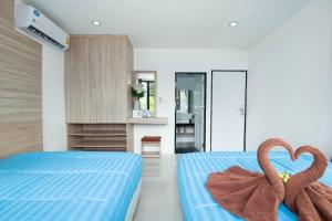 two towels in the middle of a bedroom with two beds at 94 Pool Villa in Ban Huai Yai