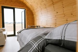 een bed in een kamer met een houten muur bij Easkey Glamping Village in Easkey