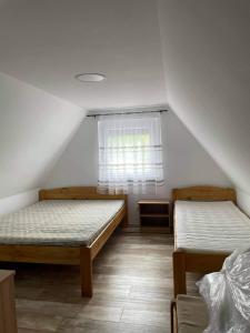 two beds in a room with a window at Tópart Nyaralóház Gyékényes in Gyékényes