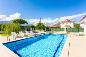 a swimming pool with chairs and an umbrella at Villa Vista in Dalyan
