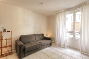 a living room with a couch and a window at Le calme et cosy avec parking gratuit in Lyon