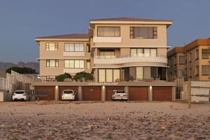 un grand bâtiment avec deux voitures garées devant dans l'établissement Jacquelena Hof 9, à Strand