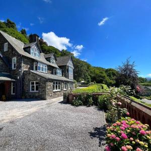 uma grande casa de pedra com flores em frente em Ravenstone Manor em Keswick