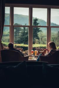 un hombre y una mujer sentados en sillas frente a una ventana en Ravenstone Manor en Keswick