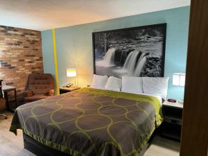 a hotel room with a bed and a painting on the wall at Super 8 by Wyndham Blytheville in Blytheville