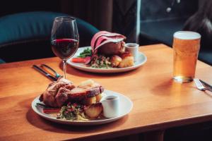 una mesa con dos platos de comida y una copa de vino en Ravenstone Manor en Keswick