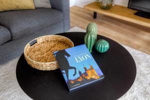 a book on a table in a living room with a cactus at Le chaleureux et cosy avec parking proche Lyon 