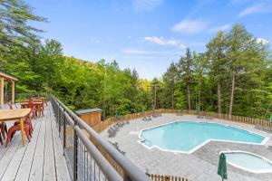 a deck with a swimming pool and a table and chairs at Huttopia Adirondacks in Lake Luzerne