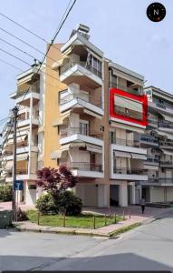 un grand immeuble d'appartements avec un panneau rouge devant lui dans l'établissement MaVitaPlace Harmonia Apartment, à Kateríni