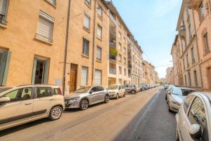 Une rangée de voitures garées sur le côté d'une rue dans l'établissement Cosy pour un week-end ou déplacement pro, à Lyon