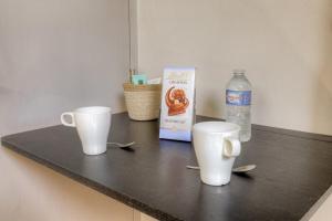 deux tasses sur un comptoir avec une boîte et une bouteille d'eau dans l'établissement Cosy pour un week-end ou déplacement pro, à Lyon