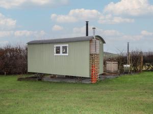 a green building with a chimney and a window at Aston - Shepherd Hut in Craven Arms
