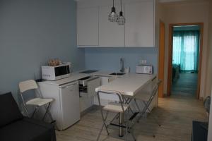 a kitchen with white cabinets and a table and chairs at Vila Mar in Vila Franca do Campo