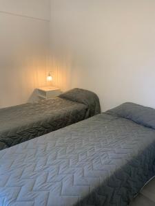 a bedroom with two beds and a table with a lamp at Hermoso y calido depto centrico in Villa Carlos Paz