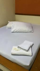 a white bed with two pillows and towels on it at Hotel Angely in Belo Horizonte