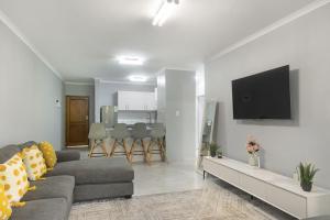 a living room with a couch and a tv on a wall at Kingston Estate 112 by HostAgents in Ballito