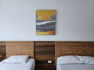 2 Betten in einem Zimmer mit einem Bild an der Wand in der Unterkunft Departamentos frente al mar Resort Playa Azul in Tonsupa