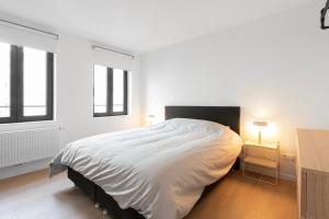 NEW apartment. UE - City center في بروكسل: غرفة نوم بيضاء بسرير كبير ونوافذ