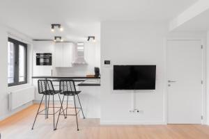 NEW apartment. UE - City center في بروكسل: مطبخ أبيض مع كرسيين بار وتلفزيون بشاشة مسطحة