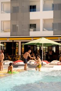 um grupo de pessoas em uma piscina com um guarda-sol em Ryans Lolas - Adults Only em Baía de San Antonio