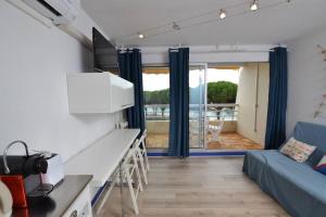 ein Wohnzimmer mit einem blauen Sofa und einer Küche in der Unterkunft La lagune vue canal et accès mer in Le Grau-du-Roi