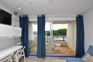 Zimmer mit blauen Vorhängen und einem Balkon mit einem Tisch in der Unterkunft La lagune vue canal et accès mer in Le Grau-du-Roi