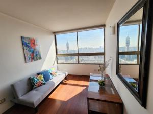 a living room with a couch and a large window at departamentos santiago centro moneda SUAGON APART HOTEL in Santiago