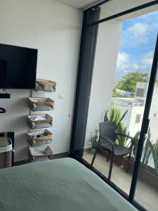 um quarto com uma cama, uma televisão e uma varanda em Precious Studio w/ working station em Playa del Carmen