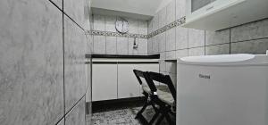 une cuisine avec une chaise et un réveil sur le mur dans l'établissement Apart Hotel Farol de Itapuã - Duas suítes com cozinha completa à 250m da praia e farol de Itapuã, à Salvador