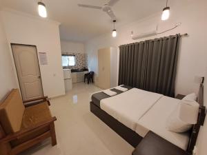a bedroom with a bed and a chair in it at Hotel RSA Residency in Pernem