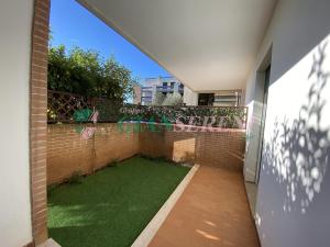 een kleine achtertuin met een groen gazon op een bakstenen muur bij AGOS in San Vincenzo