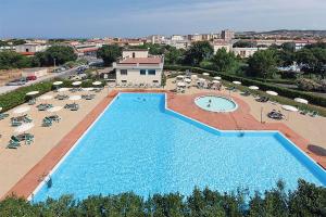 uitzicht op een groot zwembad met stoelen en parasols bij AGOS in San Vincenzo
