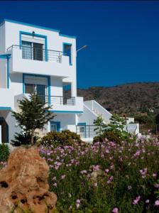 een wit huis met bloemen ervoor bij Meltemi Beach Apartments 2 in Milatos