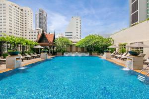a large swimming pool with chairs and buildings at The Sukosol Hotel in Bangkok