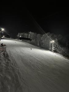a person riding a snowboard down a snow covered slope at night at Domek Poniwiec Mała Czantoria in Ustroń