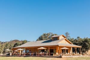 a large wooden building with tables and umbrellas at Huttopia Wine Country in Lower Lake