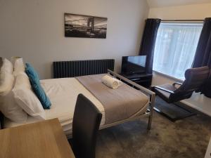 1 dormitorio con 1 cama, 1 silla y TV en Silvertree Lodge - 2 double bed flat with parking en Hemel Hempstead