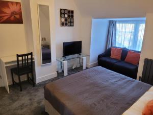 a bedroom with a bed and a couch and a television at Silvertree Lodge - 2 double bed flat with parking in Hemel Hempstead