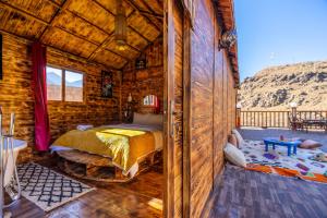 a bedroom in a log cabin with a bed at Riad Atlas Bangalo in Imlil