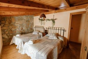 two beds in a room with a stone wall at Casa Rural El Cañico in Otero de Bodas