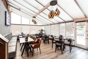 un restaurante con mesas, sillas y ventanas grandes en Village Hotel Manchester Cheadle, en Cheadle