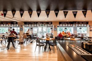 a restaurant with tables and people sitting at tables at Village Hotel Manchester Cheadle in Cheadle