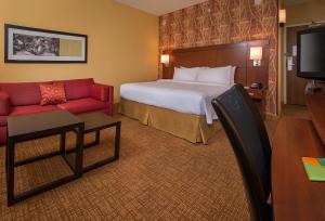 a hotel room with a bed and a red couch at Courtyard Williamsburg - Busch Gardens in Williamsburg