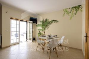 een eetkamer met een tafel en een plant aan de muur bij Villa BelaVista by ACasaDasCasas in Ericeira